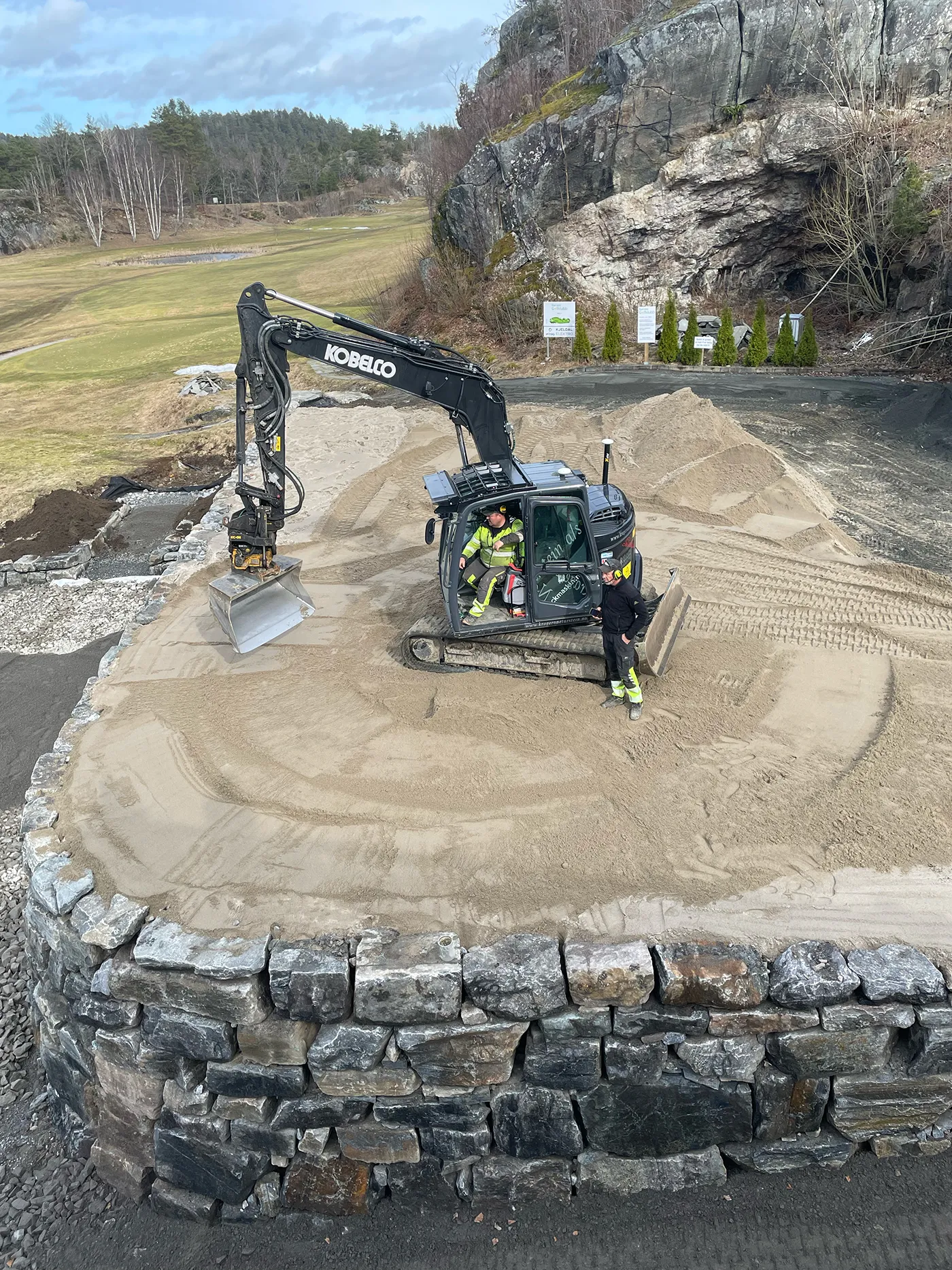 Gravemaskin som driver utbedringsarbeid på drivingrange og puttinggreen i Bamble Golfpark