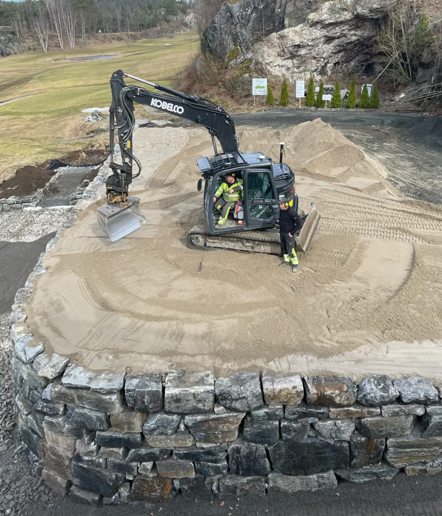 Gravemaskin i full gang med utbedringsarbeid på puttinggreen og drivingrange i Bamble Golfklubb.