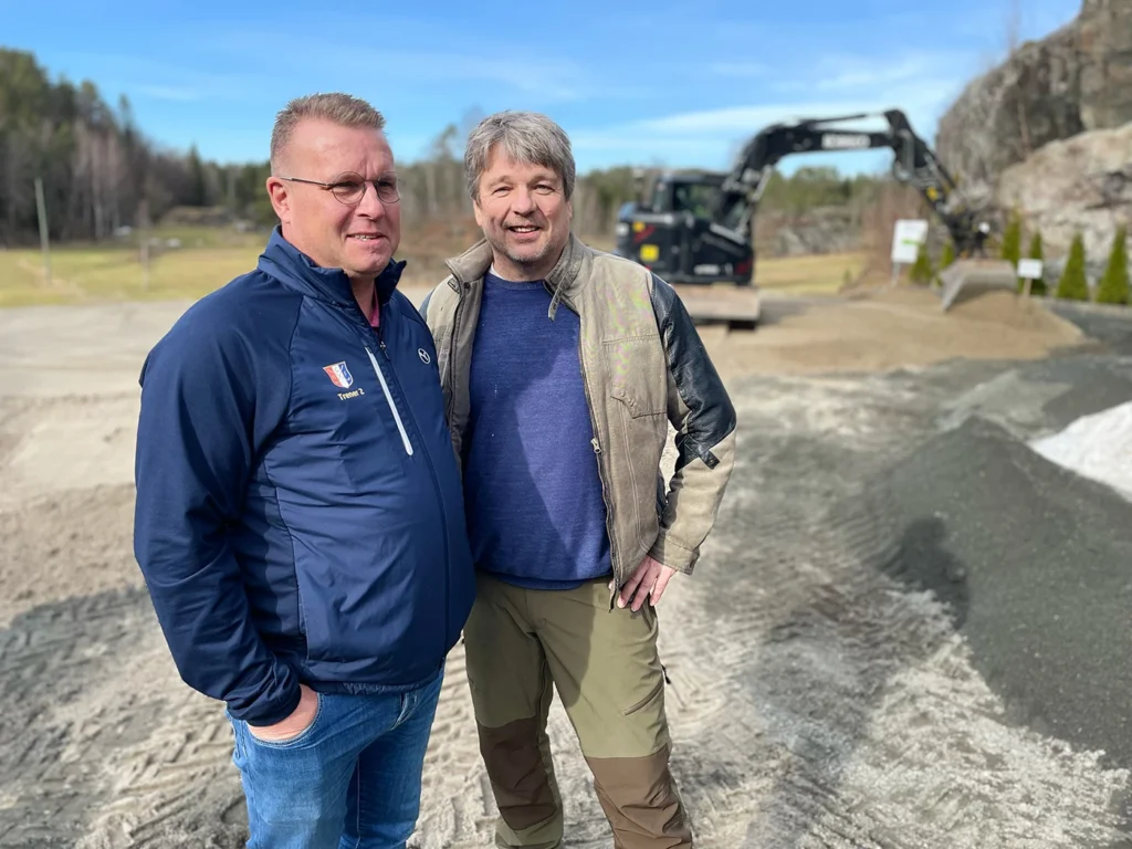 Styreleder Peter Specht og daglig leder Helge Kimerud foran gravemaskin som driver med utbedringsarbeid på treningsgreenen i Bamble Golfpark